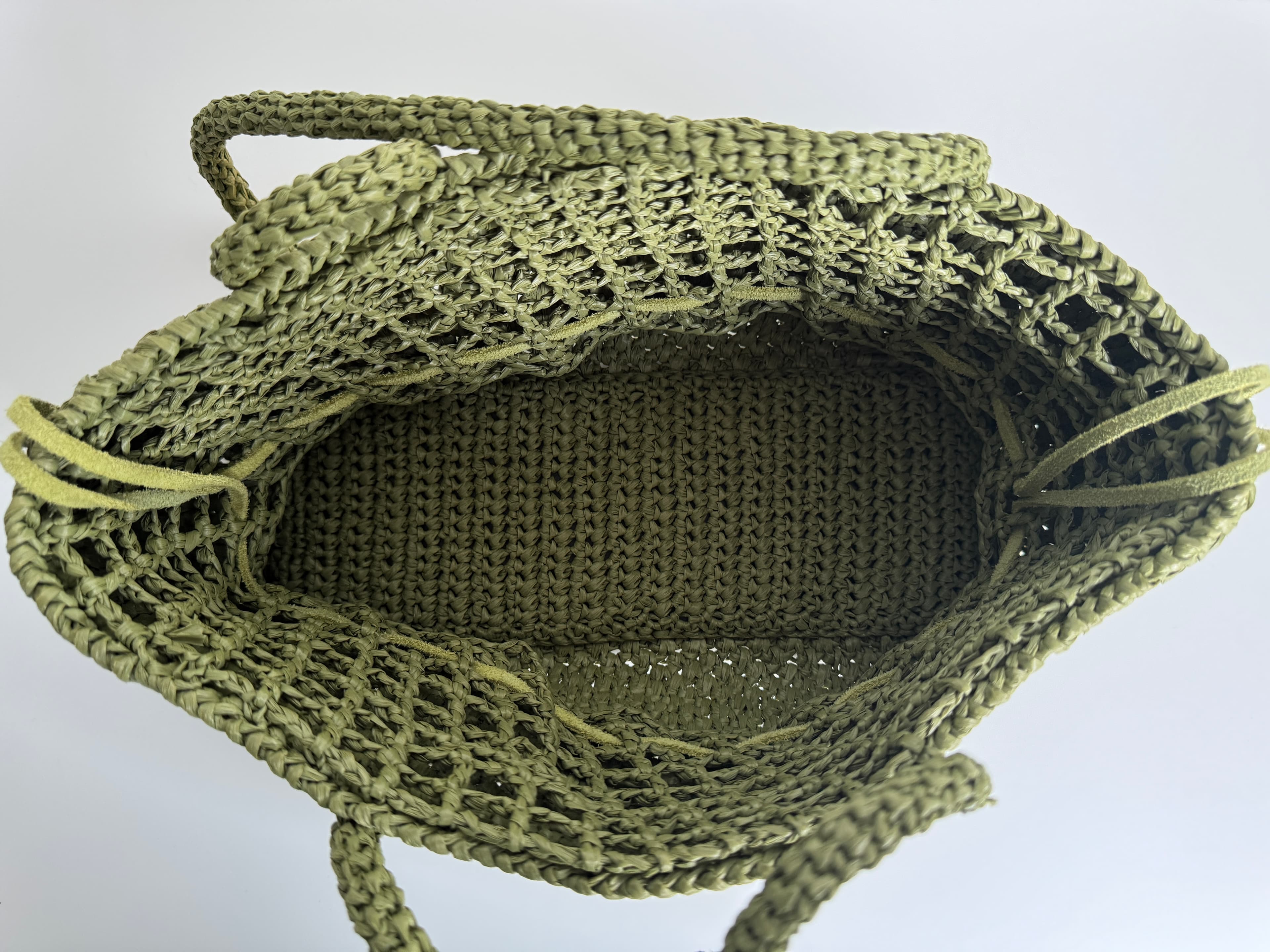 Intérieur spacieux d'un sac cabas en raphia vert olive avec des détails tressés.