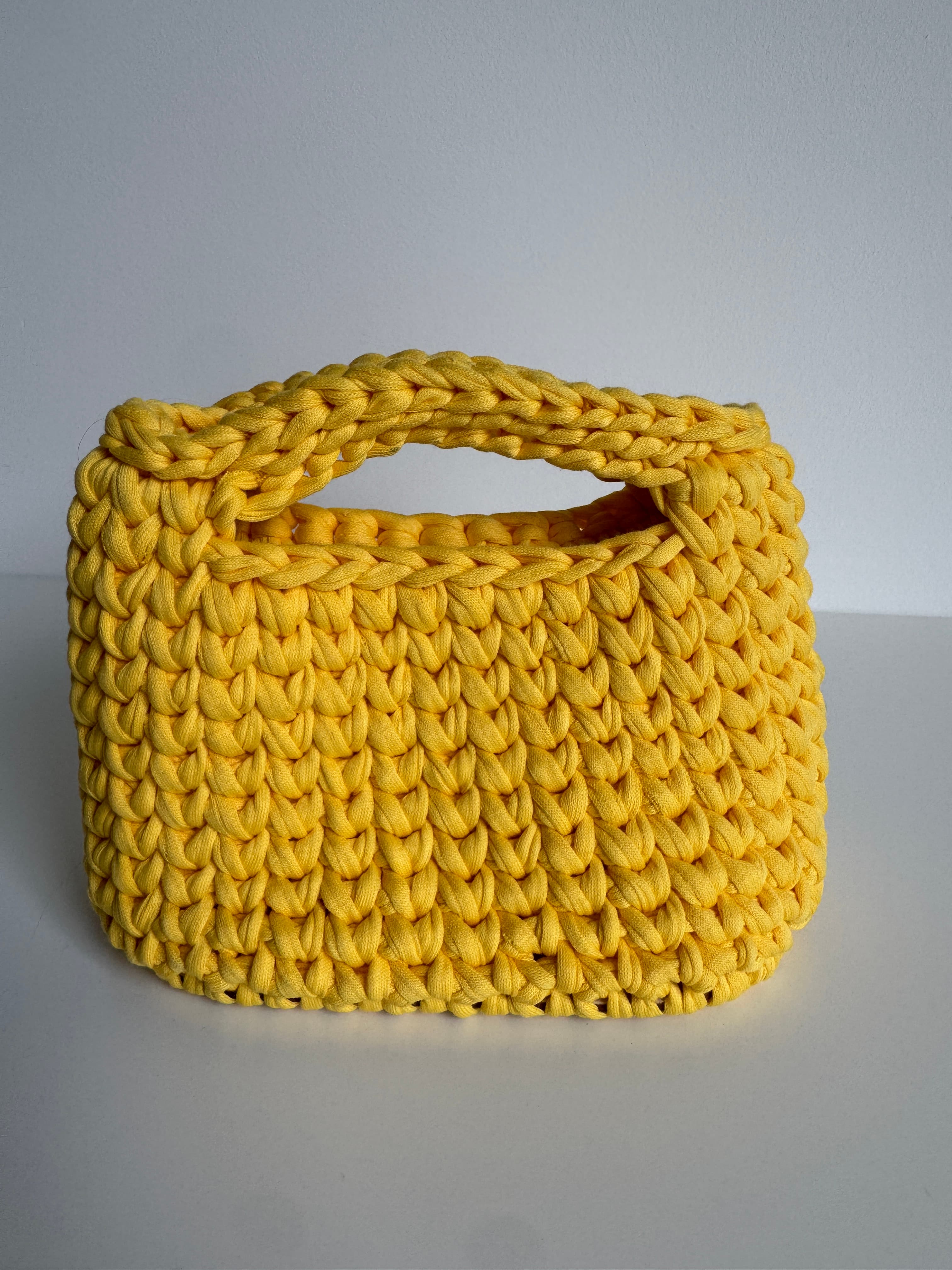 Sac à main jaune vif en grosse maille crochetée avec une anse épaisse intégrée.