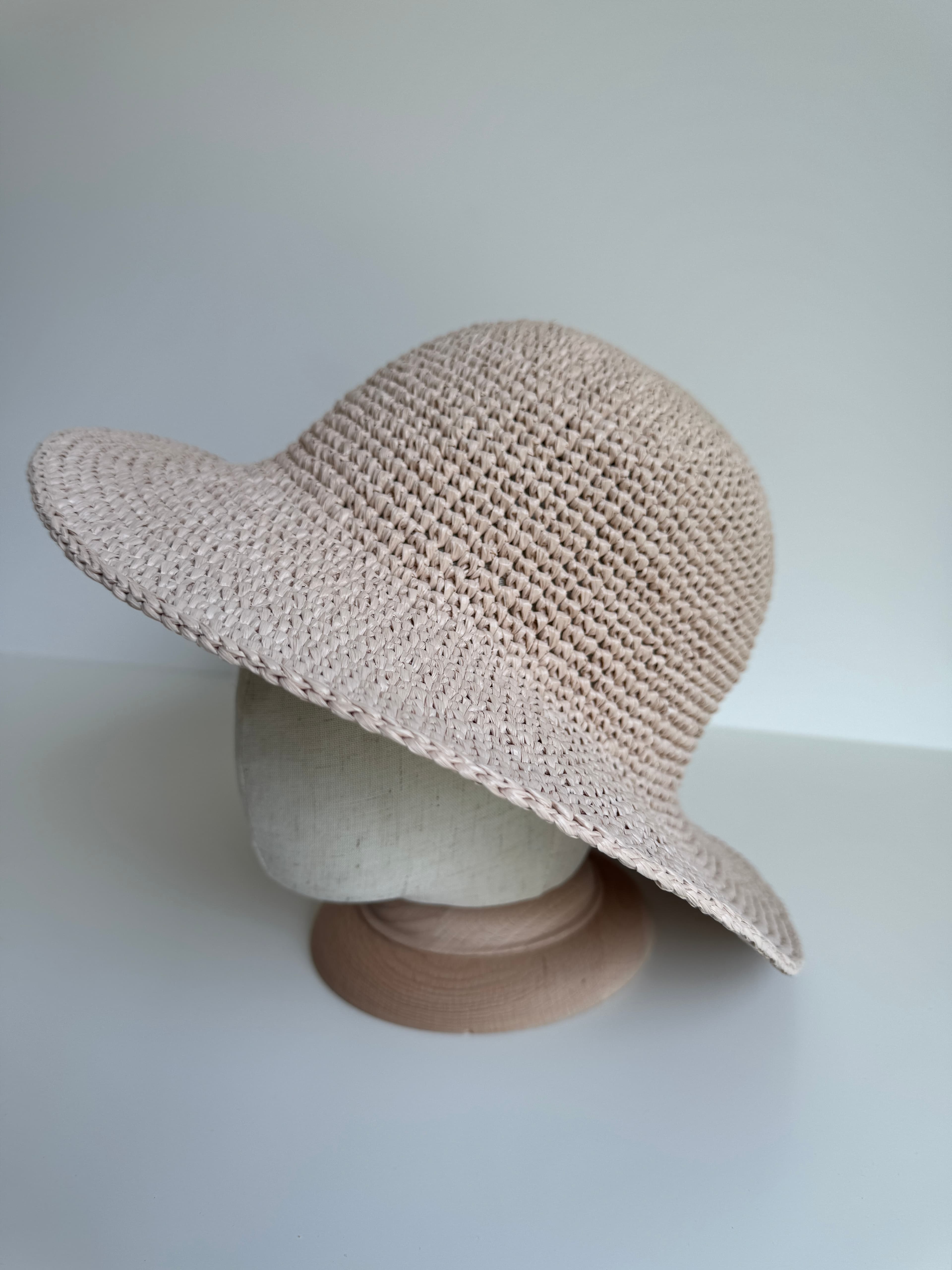 Chapeau de soleil beige en paille tressée avec un large bord sur un mannequin.