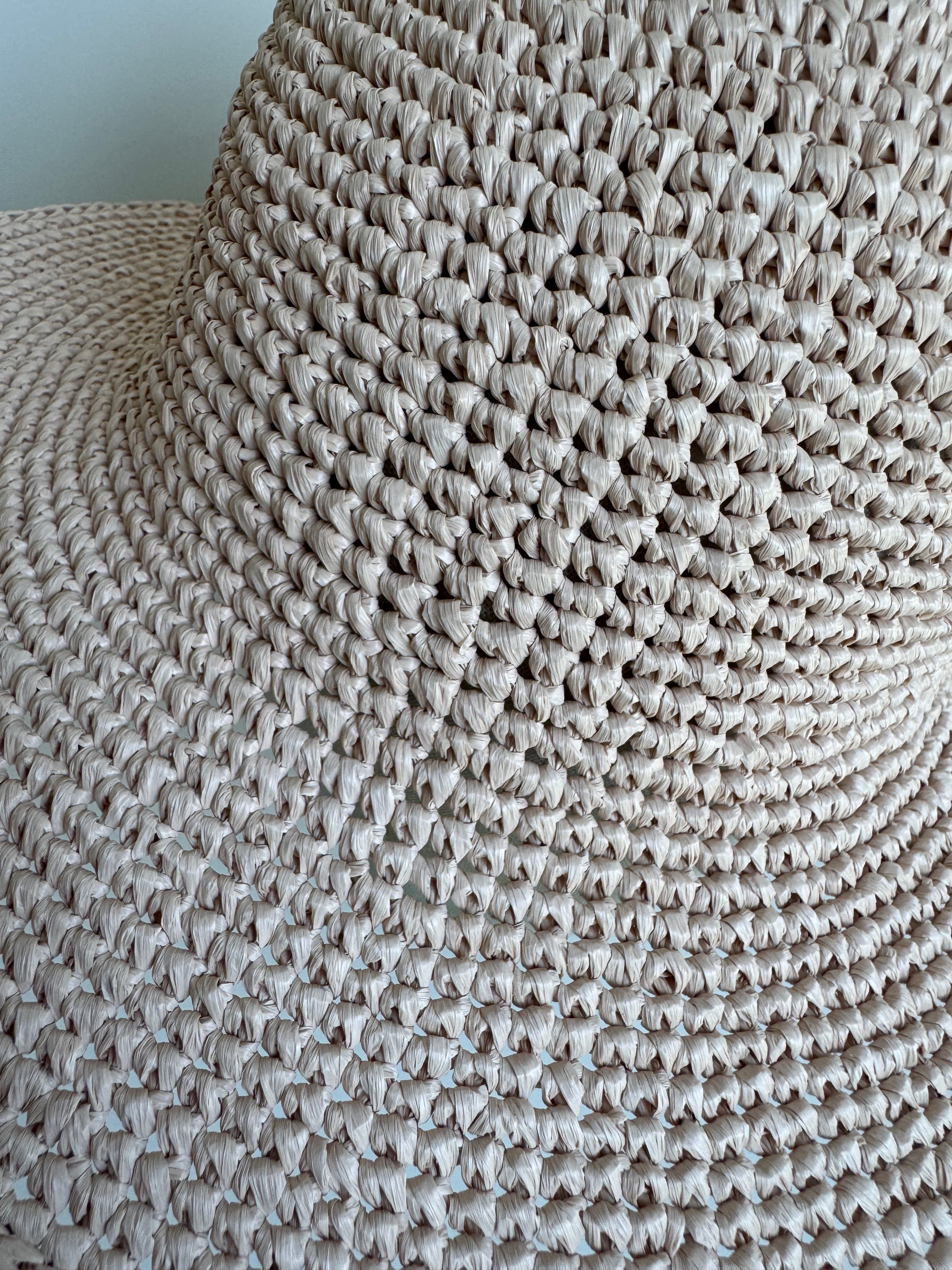 Gros plan sur la texture détaillée et le tissage serré d'un chapeau de paille beige.